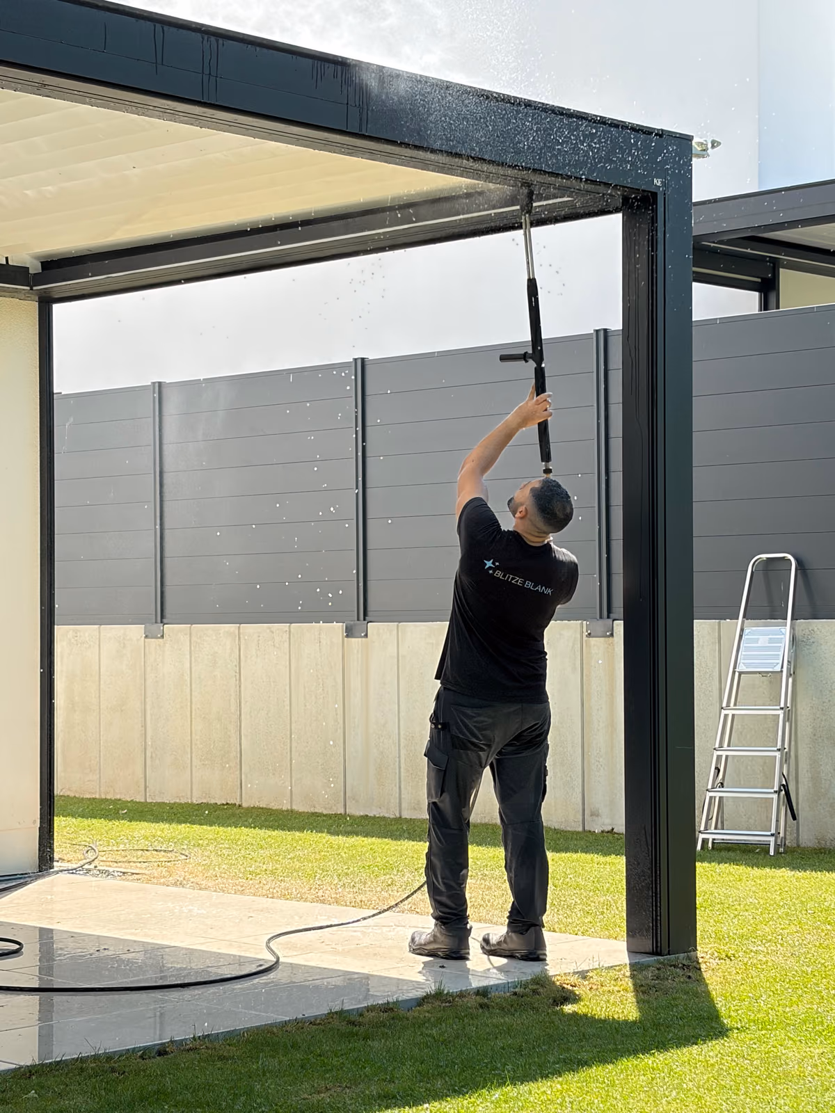 Blitzeblank employee cleaning a pergola roof with a high-pressure telescopic lance