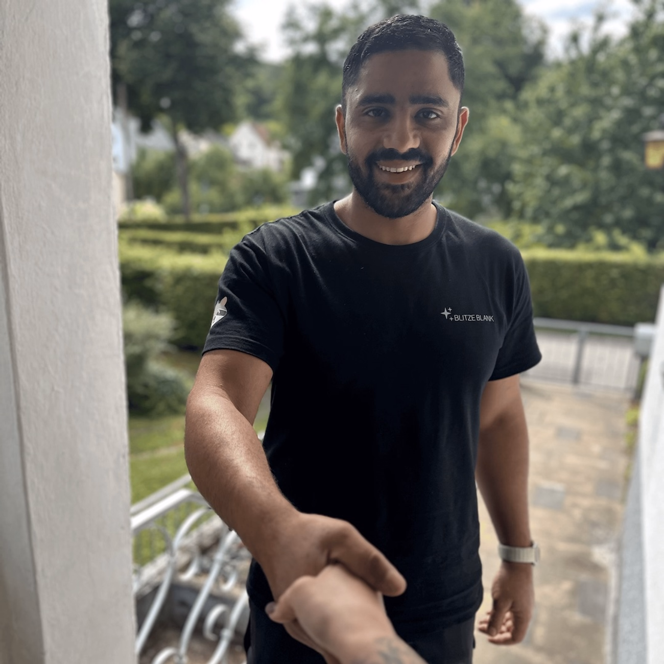 Mustapha El-Ali, Gründer und Geschäftsführer von Blitzeblank, im schwarzen Firmen-Shirt mit ausgestreckter Hand zur Begrüßung